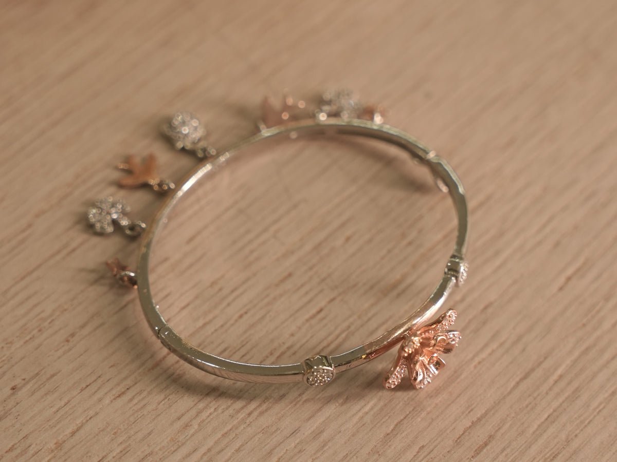 Close view of a rose-tone lily with pave set petals on the silver bracelet.