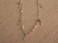 Delicate two-tone chain bracelet with starburst discs, clover links and safety pin shaped connectors.