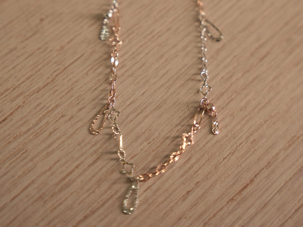 Delicate two-tone chain bracelet with starburst discs, clover links and safety pin shaped connectors.