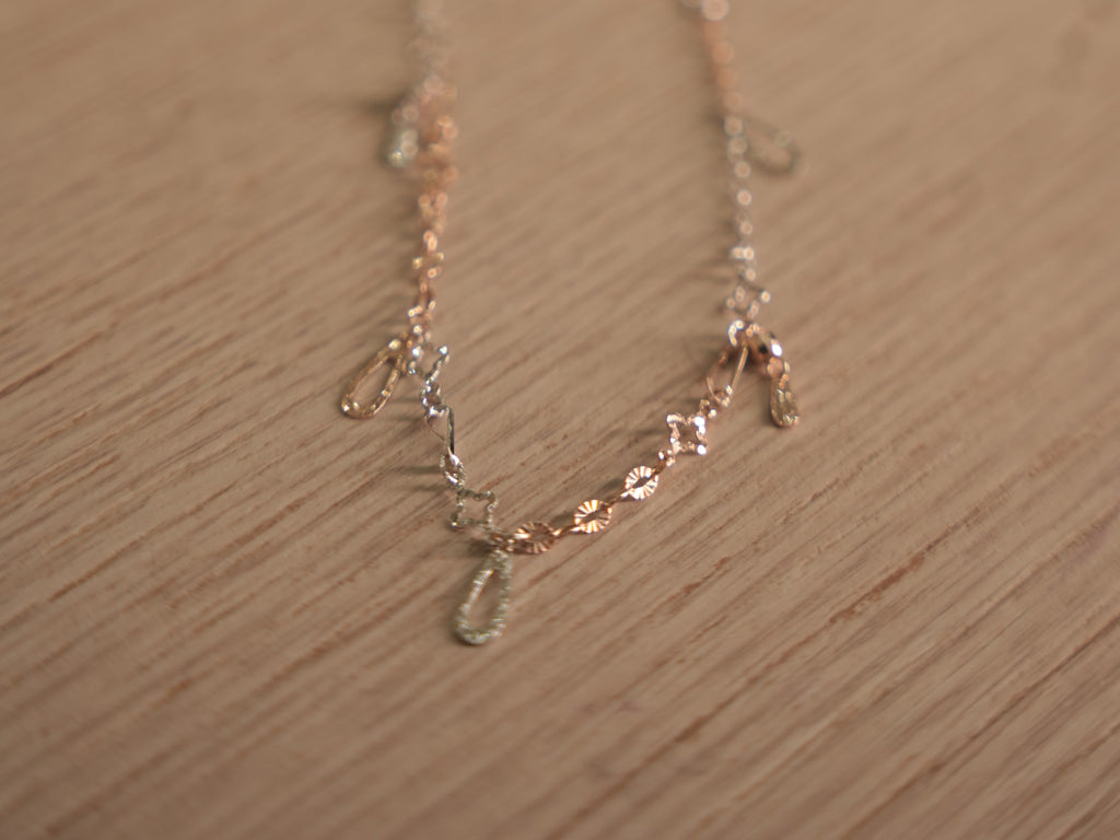 The full length of the two-tone chain bracelet laid out on a pale surface.