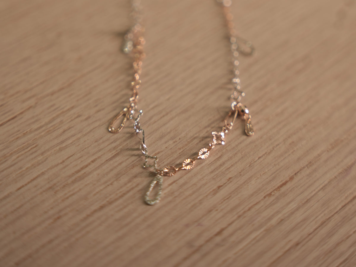 The full length of the two-tone chain bracelet laid out on a pale surface.