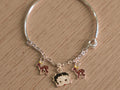 Kids silver bracelet with a chain section carrying enamelled deer charms and a cartoon doll face.