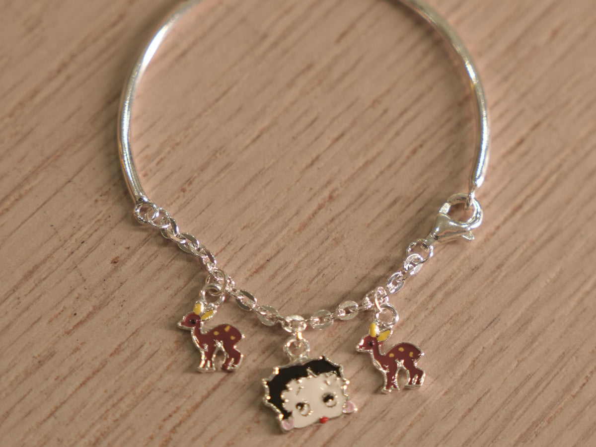 Kids silver bracelet with a chain section carrying enamelled deer charms and a cartoon doll face.