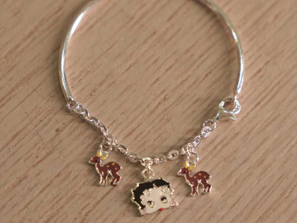 Kids silver bracelet with a chain section carrying enamelled deer charms and a cartoon doll face.