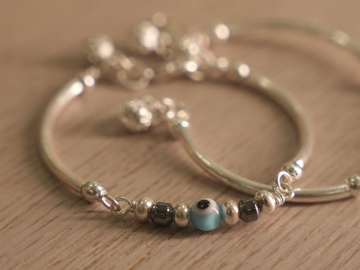 Two matching baby silver nazariya bangles with evil eye beads and ghungroo drops, shown together.