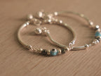 Close view of the evil eye glass bead between dark beads on the baby bangle.