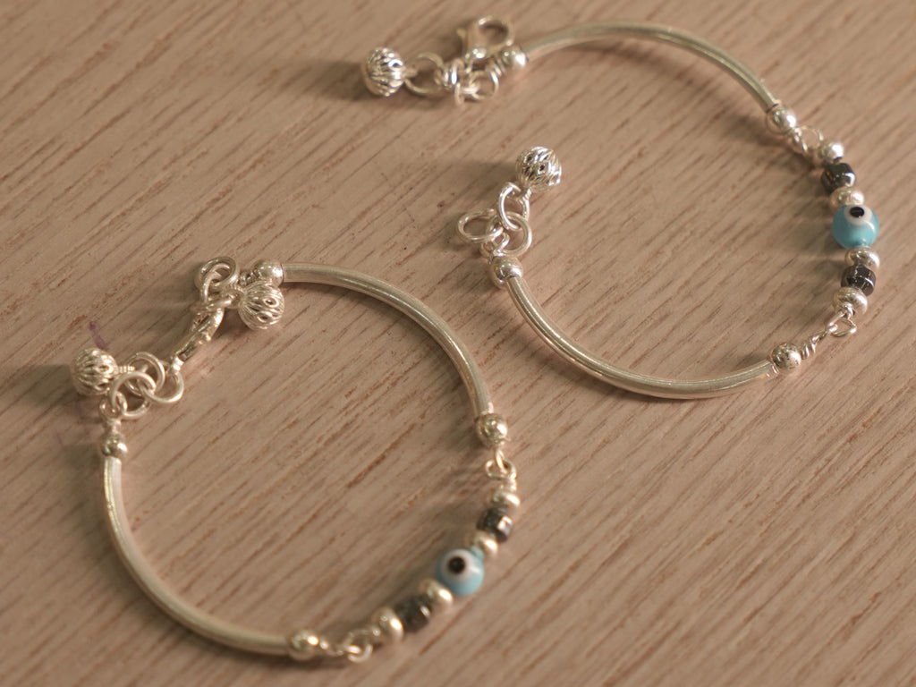 A baby nazariya bangle standing upright, showing its slim curved tubes and bead station.