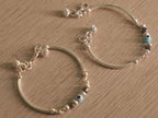 A baby nazariya bangle standing upright, showing its slim curved tubes and bead station.