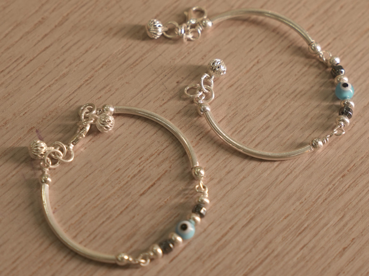 A baby nazariya bangle standing upright, showing its slim curved tubes and bead station.