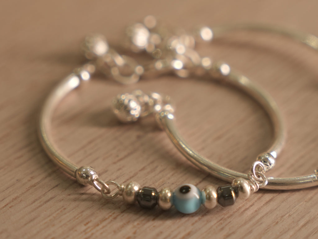 Detail of the evil eye bead, dark beads and silver rounds strung on the bangle.