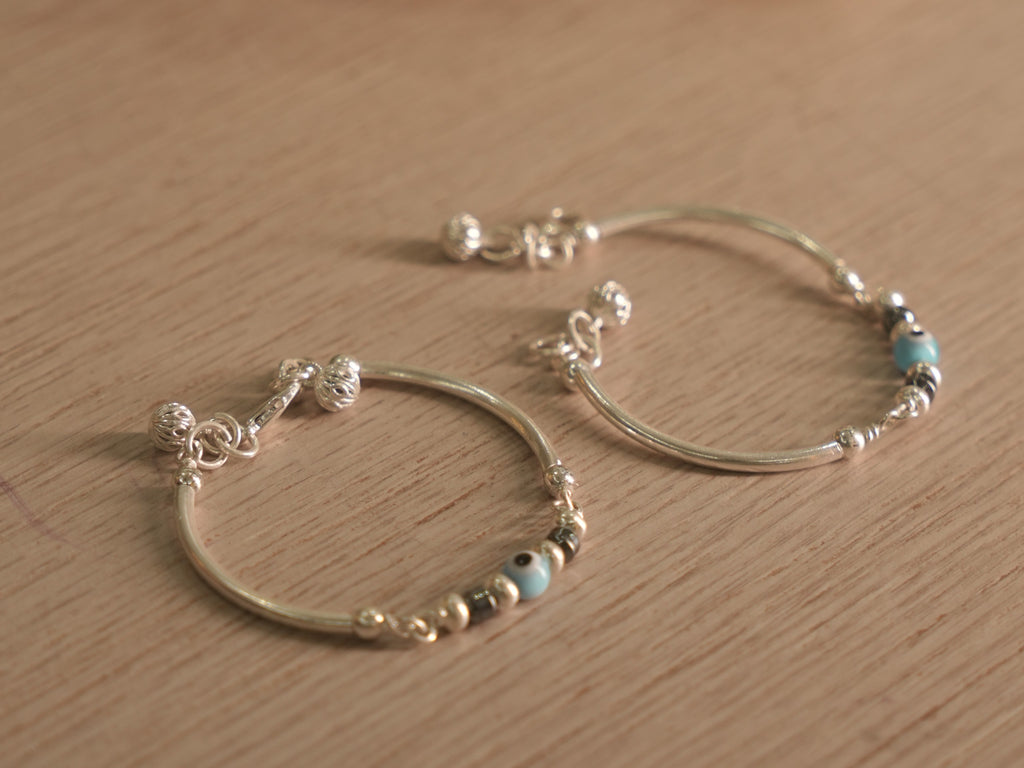 Both baby nazariya bangles resting together on a pale wooden surface.
