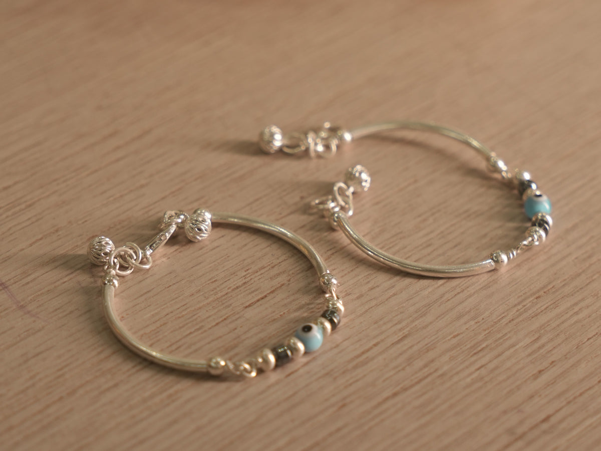 Both baby nazariya bangles resting together on a pale wooden surface.