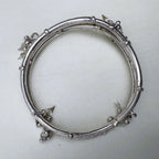The twin-tube silver kada seen from above, showing the charms at the joints.