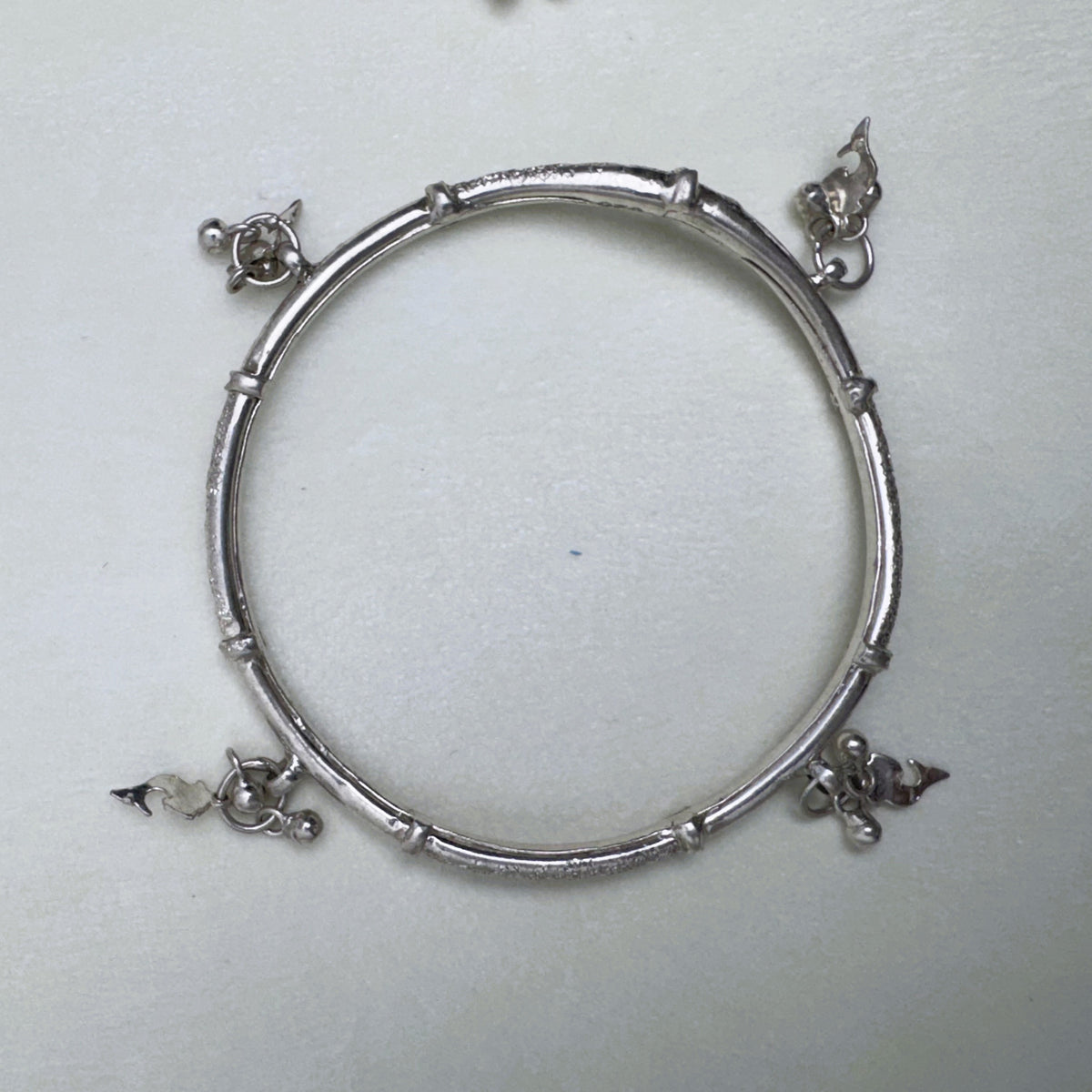 The silver kada seen from above, showing the four charm points around the ring.