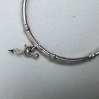 A leaf charm and the join between a textured and a polished section of the kada.