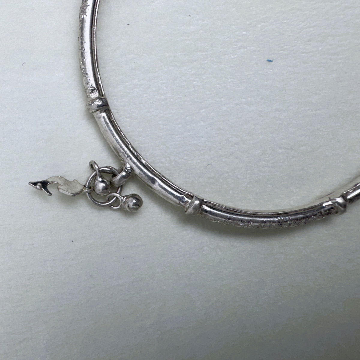 A leaf charm and the join between a textured and a polished section of the kada.