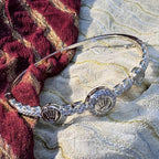 The crown medallion bangle resting on red and cream fabric, showing the halo around the centre medallion.