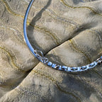 The hinge and box clasp on the plain polished back of the silver bangle.
