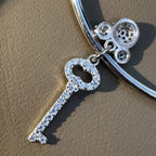 Close view of the pave set key charm and the cartoon character charm above it.