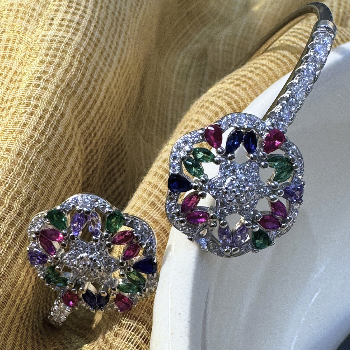 Close view of the pink, green, blue and purple marquise stones in the two flowers of the silver cuff.