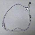 Sterling silver double snake chain bracelet with a love knot, laid open with the lobster clasp and extender.