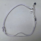 Sterling silver double snake chain bracelet with a love knot, laid open with the lobster clasp and extender.
