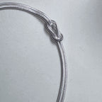 Close view of the reef knot tied in the two silver snake chains.