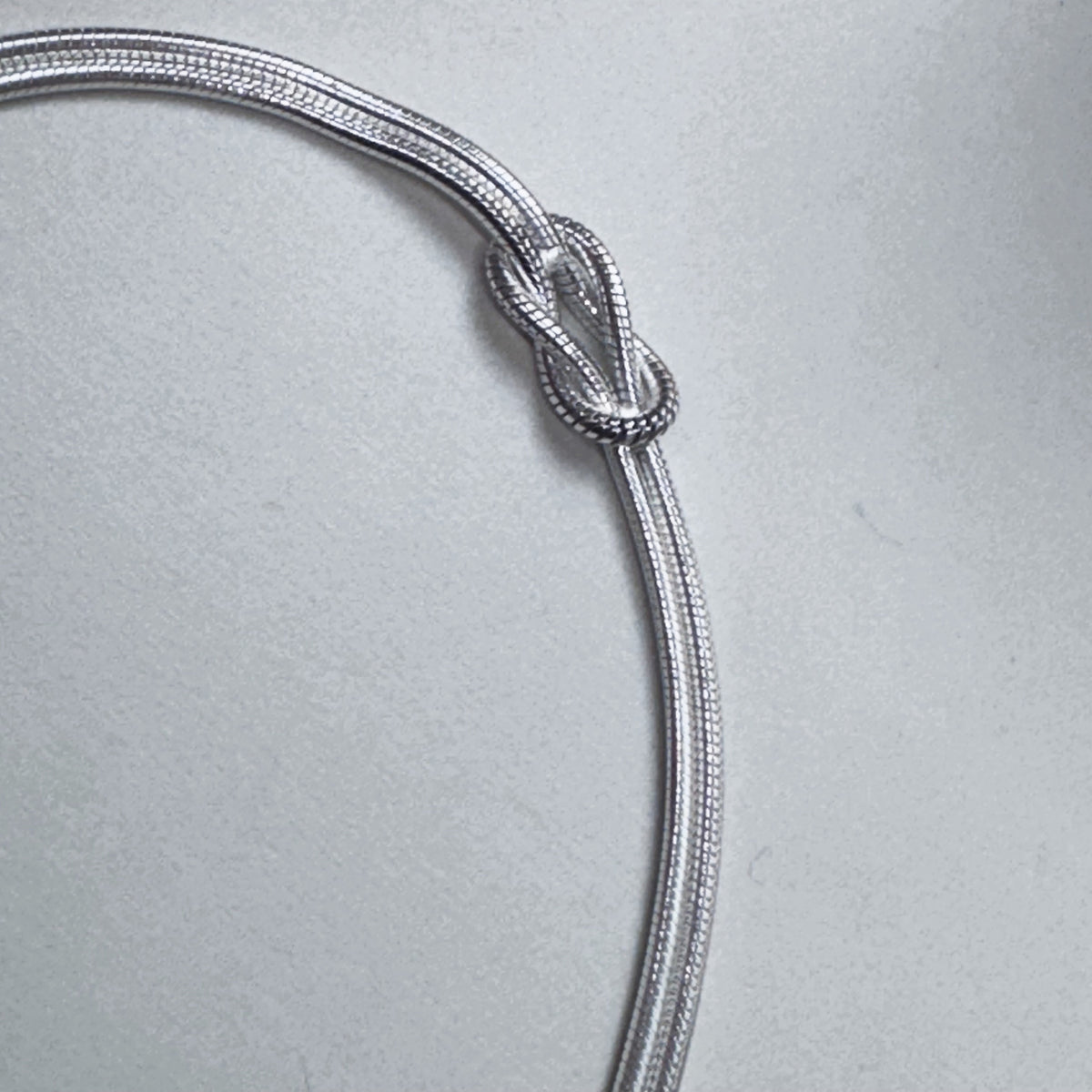 Close view of the reef knot tied in the two silver snake chains.