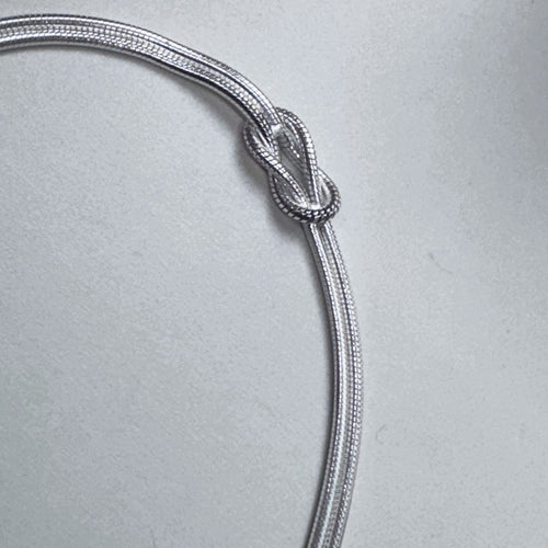 Close view of the reef knot tied in the two silver snake chains.