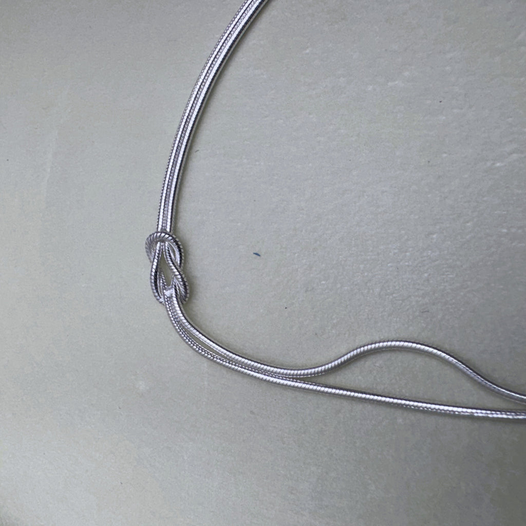 The two snake chains of the bracelet running side by side to the knot.