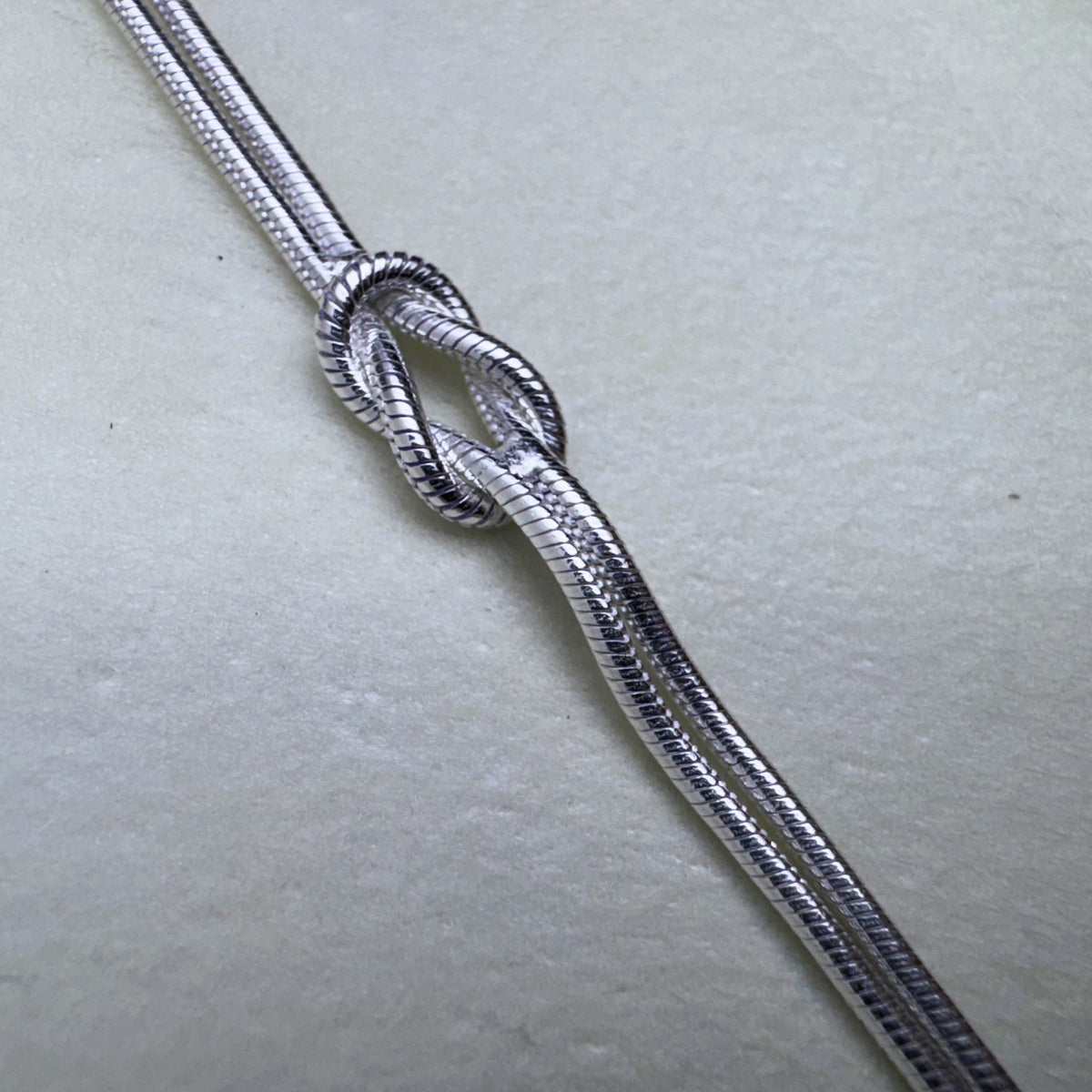 Close view of the knot and the fine texture of the snake chains.