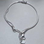 The love knot bracelet laid in a loop with the clasp and extender chain at the bottom.