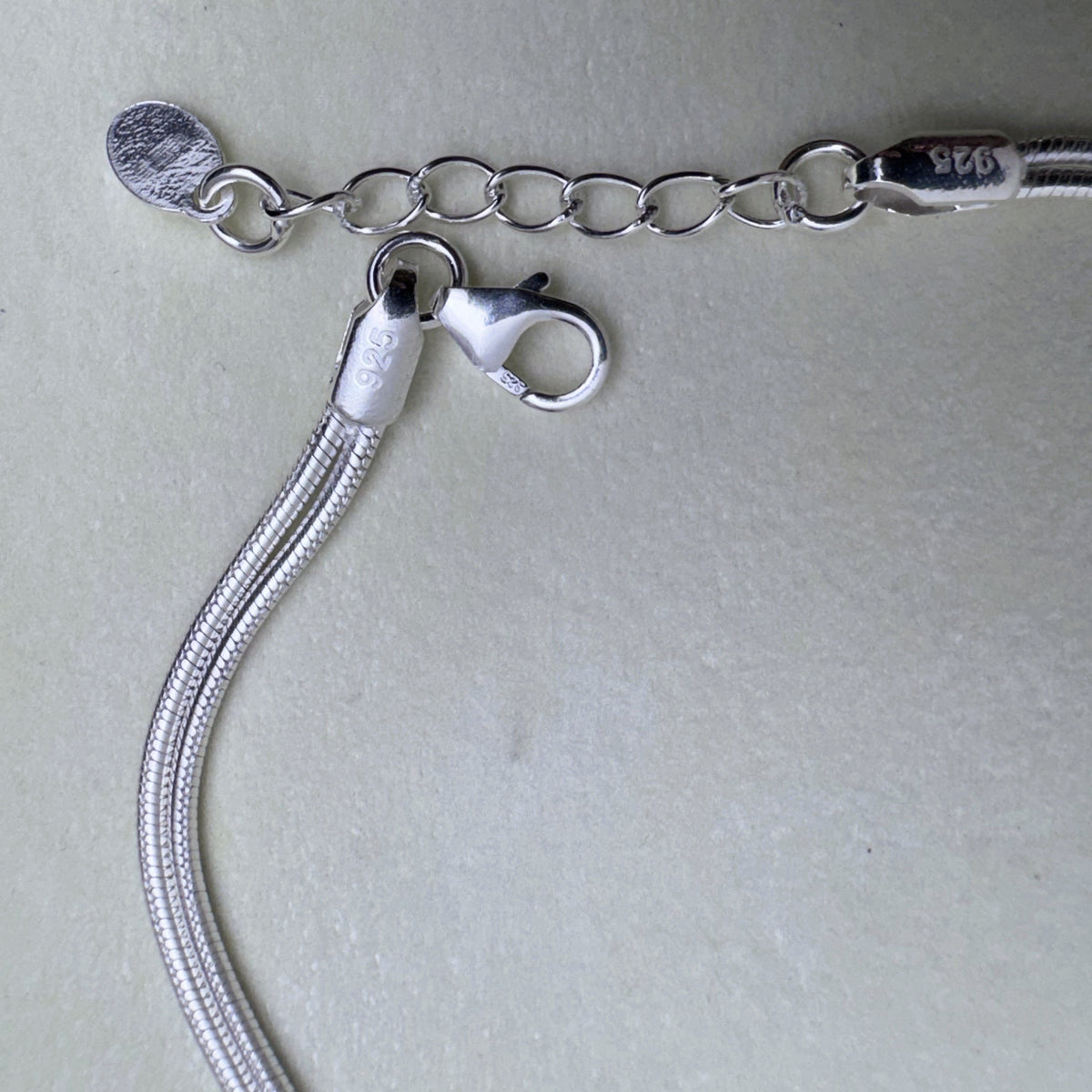 The lobster clasp, the extender chain and the 925 tag of the silver bracelet.