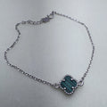 Sterling silver chain bracelet with a green glass clover in a beaded frame, laid in a loop with its clasp and extender.