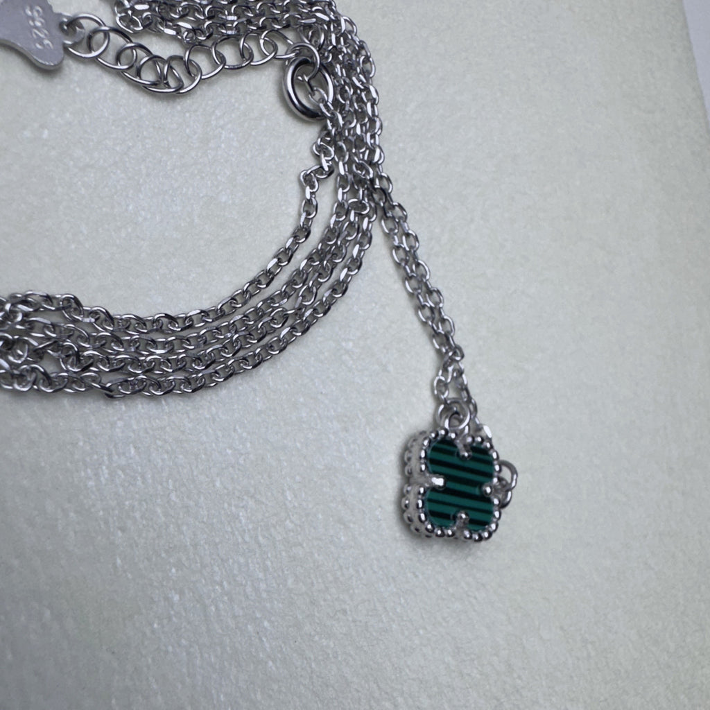 The cable chain of the green clover bracelet gathered with the matching necklace chain.