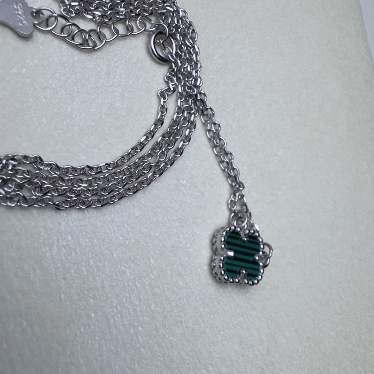 The cable chain of the green clover bracelet gathered with the matching necklace chain.