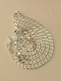 Sterling silver flat curb chain coiled on a pale surface, with the lobster clasp at the edge.