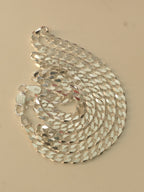 Sterling silver flat curb chain coiled on a pale surface, with the lobster clasp at the edge.