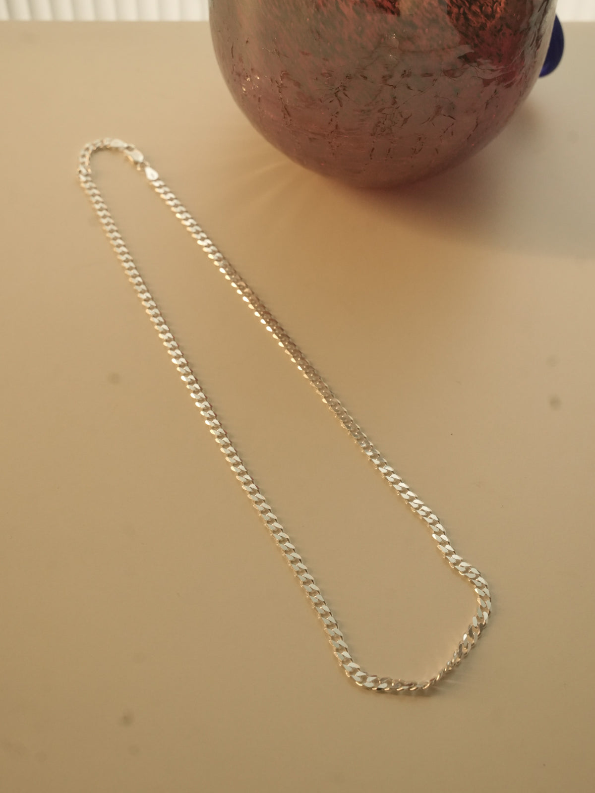 The silver curb chain laid out in a long oval to show how it falls.