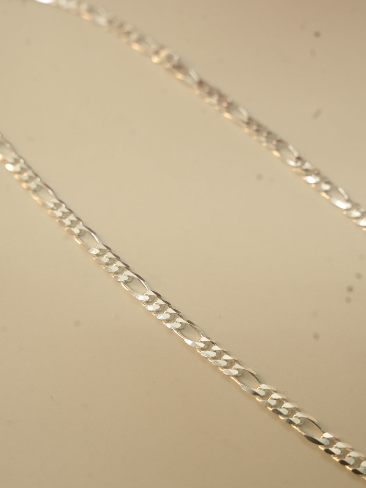 Close view of the figaro links, three short links followed by one long link.