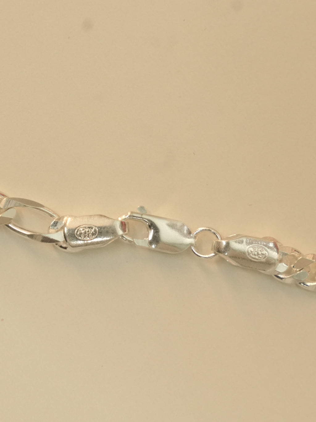 Close view of the lobster clasp and the stamped end tabs on the figaro chain.
