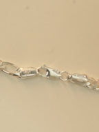 Close view of the lobster clasp and the stamped end tabs on the figaro chain.