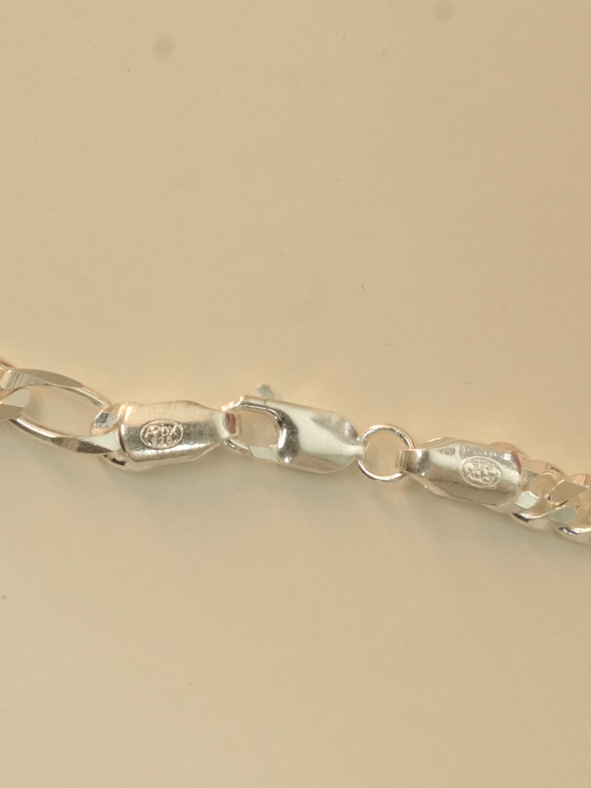 Close view of the lobster clasp and the stamped end tabs on the figaro chain.