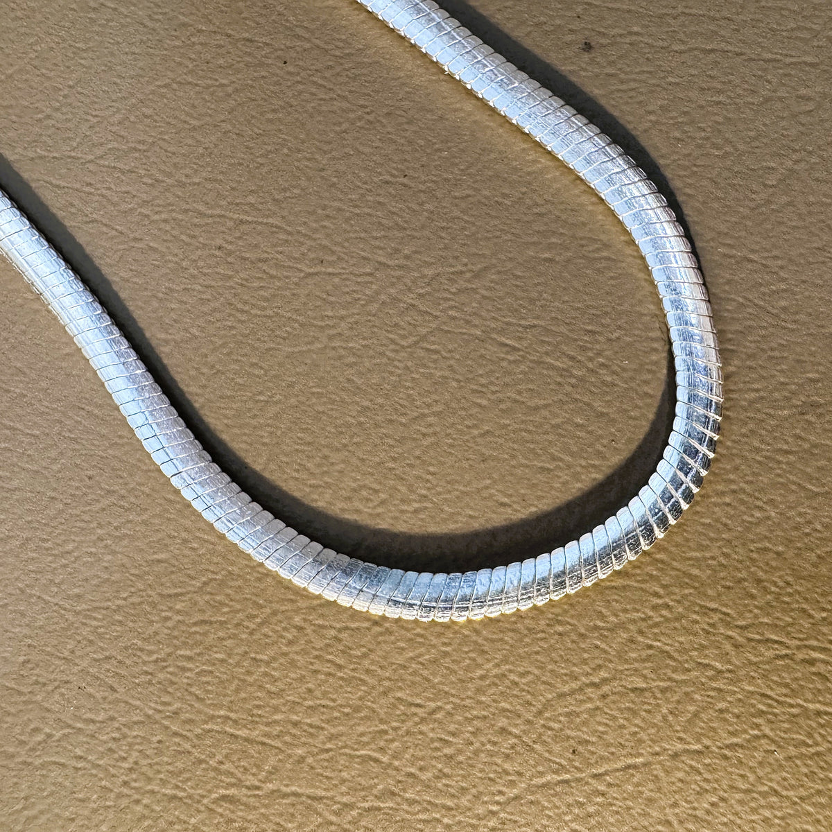 Close view of the flat slanting links of the sterling silver herringbone chain.