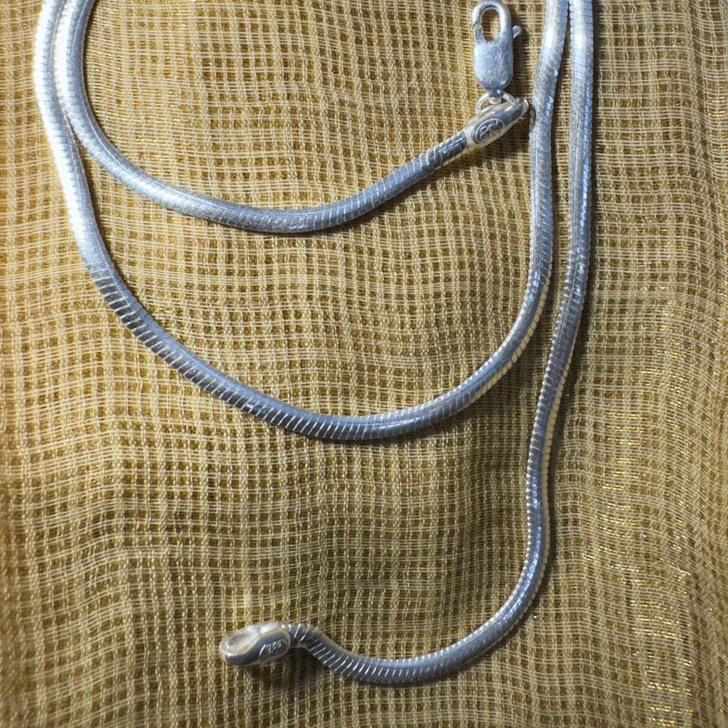 The herringbone chain laid out on cream fabric with the clasp and the 925 end tab.