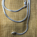 The herringbone chain laid out on cream fabric with the clasp and the 925 end tab.