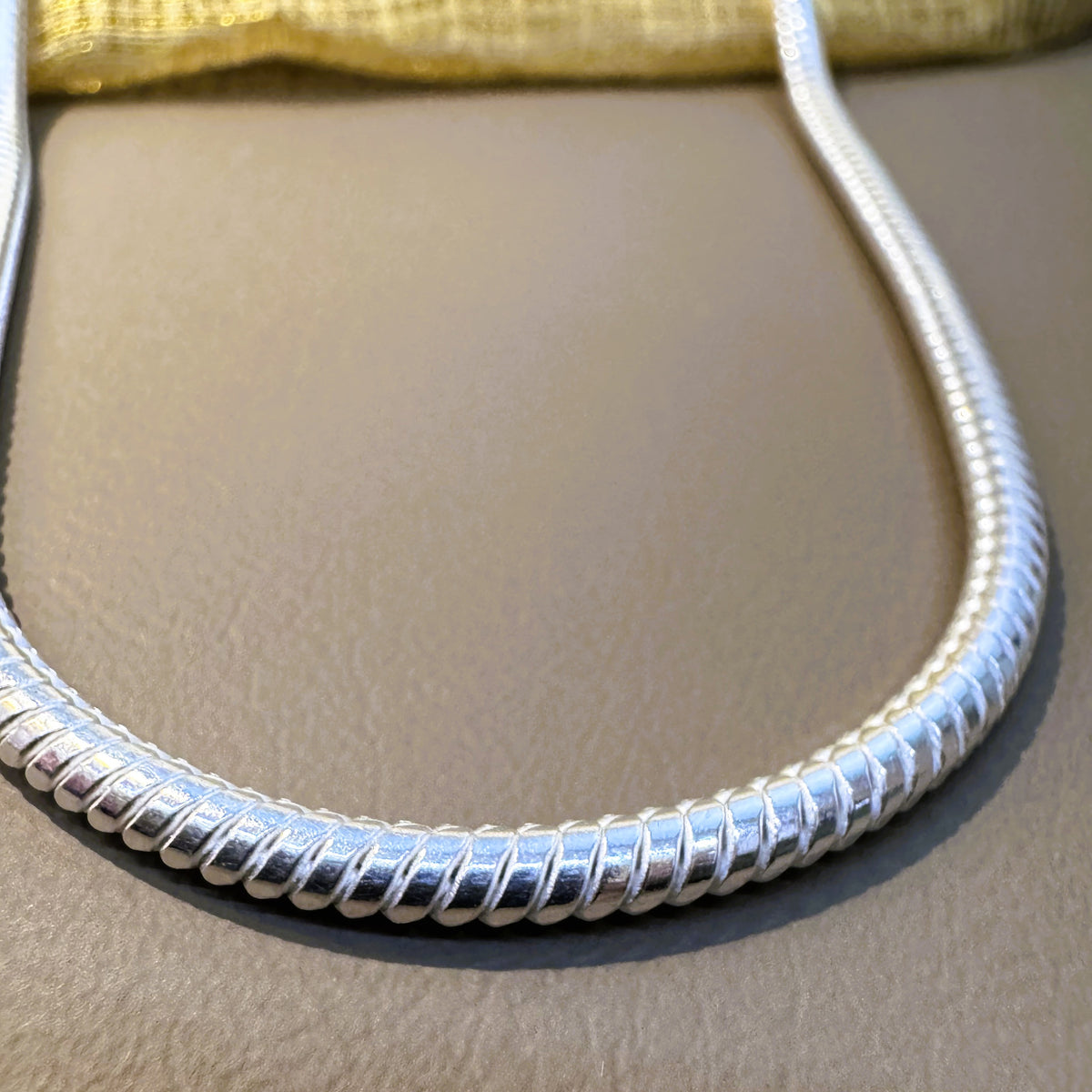 Close view of the ribbed surface of the silver omega snake chain.