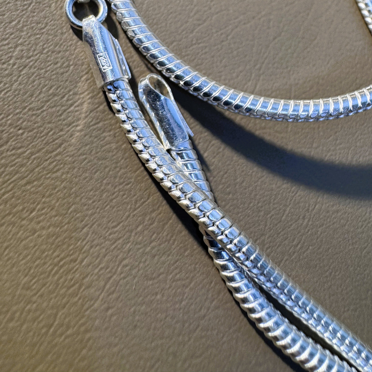 The lobster clasp and end tabs of the silver omega snake chain.