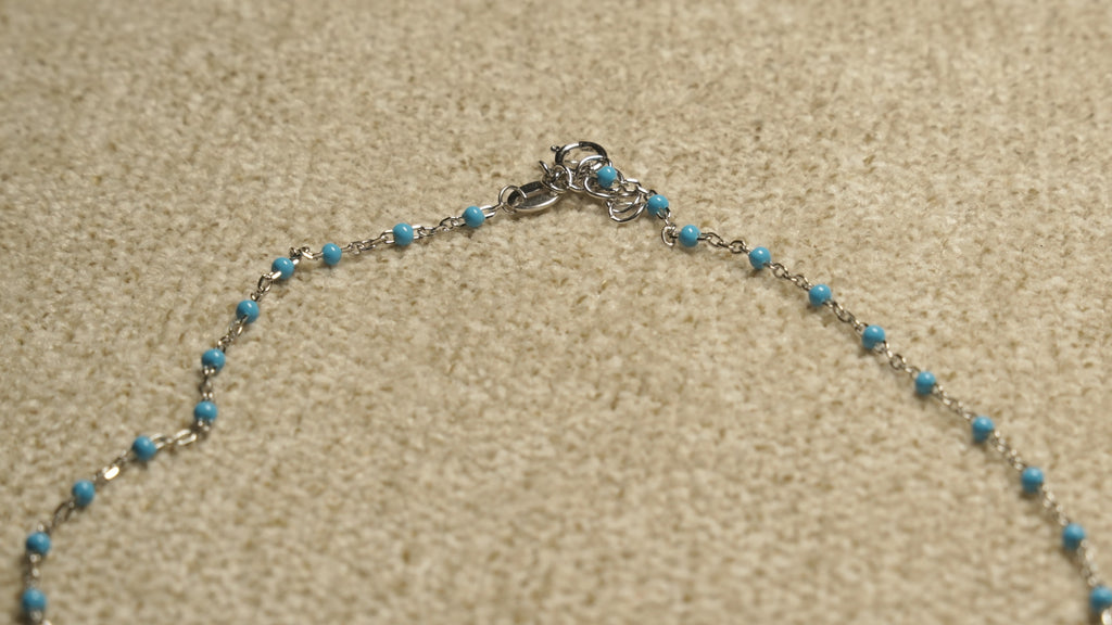 Close view of the spring-ring clasp and turquoise-blue beaded sections of the sterling silver shell chain.