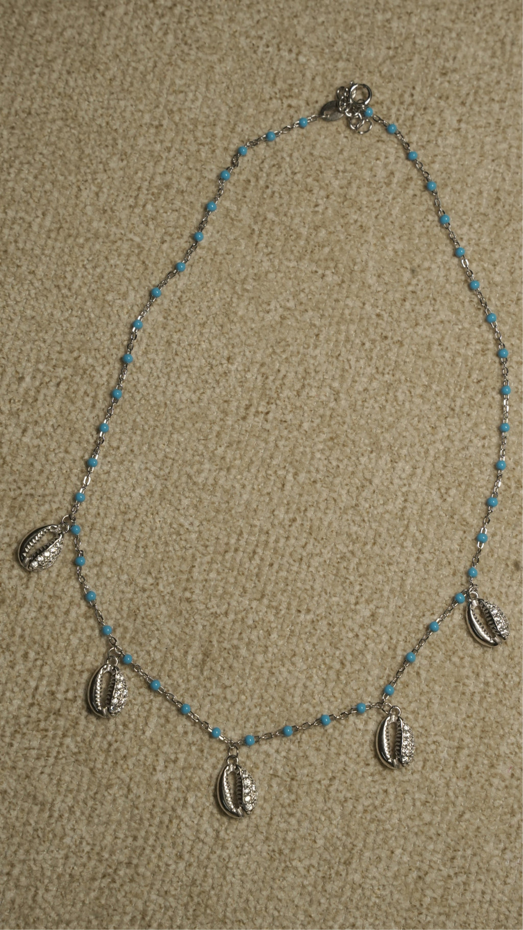 Full view of the beaded sterling silver chain with cubic zirconia-set shell charms spaced along the lower edge.